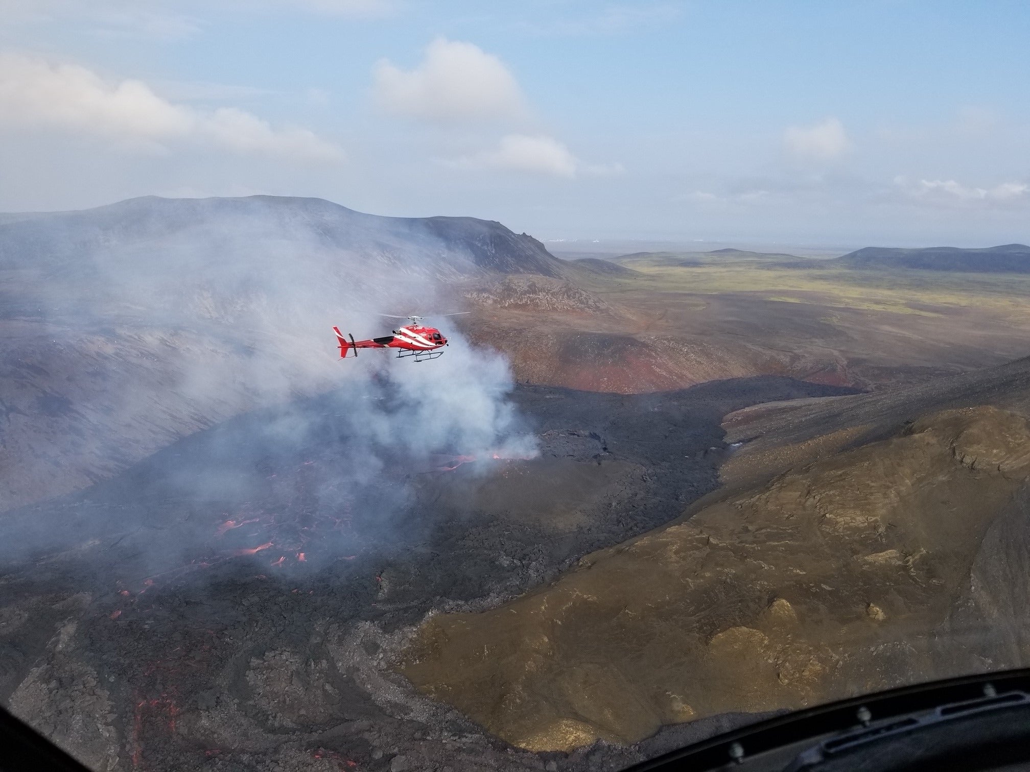 A helicopter flies close to the volcano in Iceland.