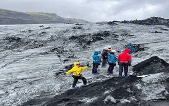 A traveler poses for a photo while exploring the Solheimajokull Glacier.