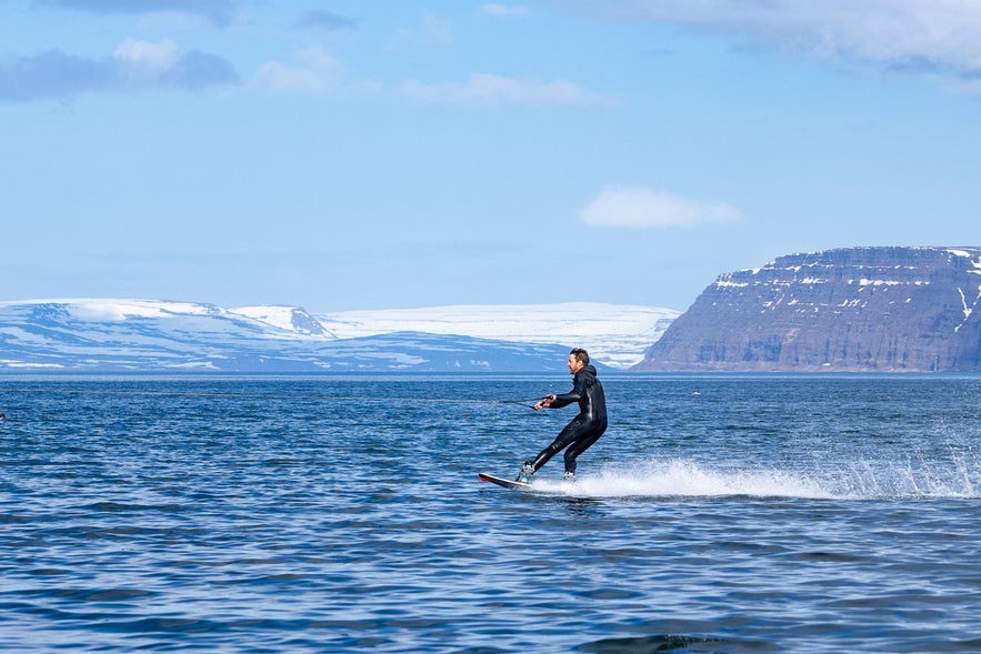 Man wakeboarding in the Westfjords, a thrilling shore excursion for travelers exploring Iceland by cruise ship.