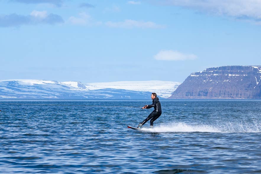 Homme pratiquant le wakeboard dans les Fjords de l’Ouest, une excursion à terre riche en sensations pour les voyageurs en croisière en Islande.