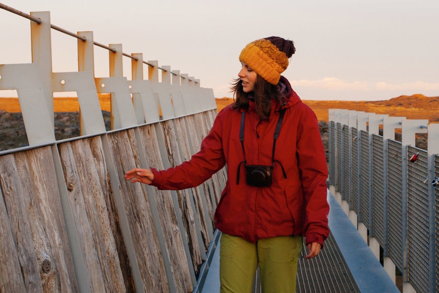 Woman standing on the Bridge Between Continents in Reykjanes Peninsula, Iceland, during sunrise in autumn.