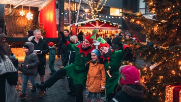 A child poses with two elves during a Christmas tour in Reykjavik.