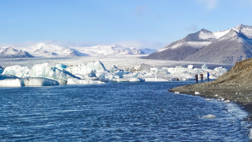 People stand near the edge of Jokulsarlon glacier lagoon.