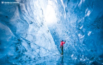 Een reiziger geniet van het verkennen van de kristalblauwe Westelijke IJsgrot in de Vatnajokull-gletsjer.