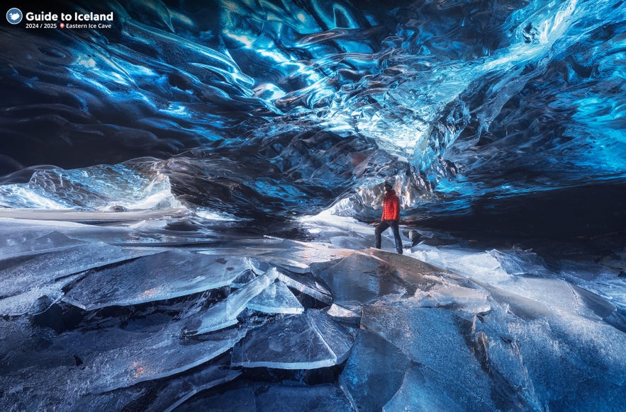 A person in a red jacket explores a blue ice cave under Vatnajokull Glacier, surrounded by shimmering ice walls and floor.