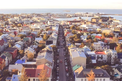 Reykjavik's colorful city lights reflect on the calm harbor waters at nighttime.