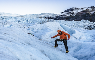 Ein Mann mit roter Jacke klettert im Skaftafell-Naturreservat auf das Eis.