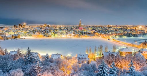 Bright lights fill the snow-covered Reykjavik city.