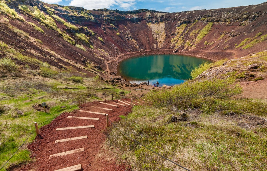Kerid Crater Lake on the Golden Circle near Thingvellir National Park in Iceland with red volcanic slopes and turquoise water.
