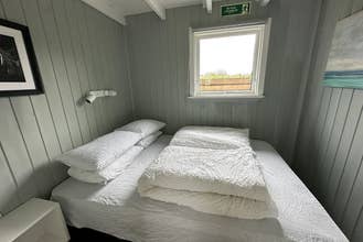 Cave Cabins一间双人卧室，床上整齐叠放着床品。