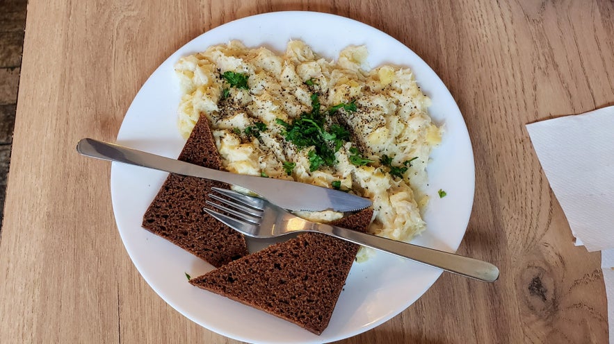 Close up from top down of a plate with an iceland dish called Plokkfiskur, a hearty fish stew and rye bread.