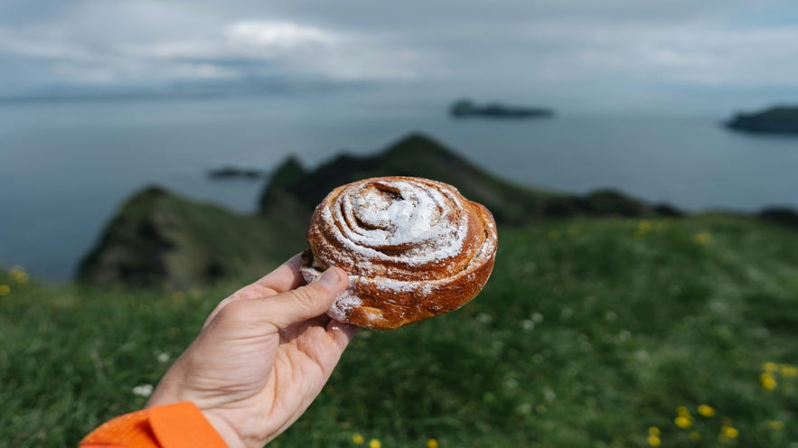 Icelandic cinnamon bun in the foreground with islands inthe backgrounds