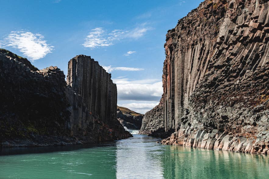 De Stuðlagil-kloof in Oost-IJsland met een smaragdgroene rivier en basaltwanden onder een heldere hemel, met uitzicht stroomopwaarts richting de waterval in de zomer. De Stuðlagil-kloof in Oost-IJsland met een smaragdgroene rivier en basaltwanden onder een heldere hemel, met uitzicht stroomopwaarts richting de waterval in de zomer.