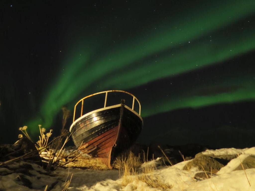 The northern lights above the wooden boat at Fisherman's Village.