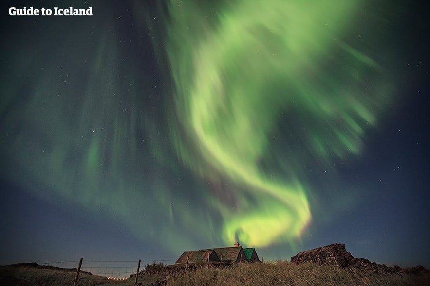 Die Nordlichter tanzen über einem isländischen Haus.