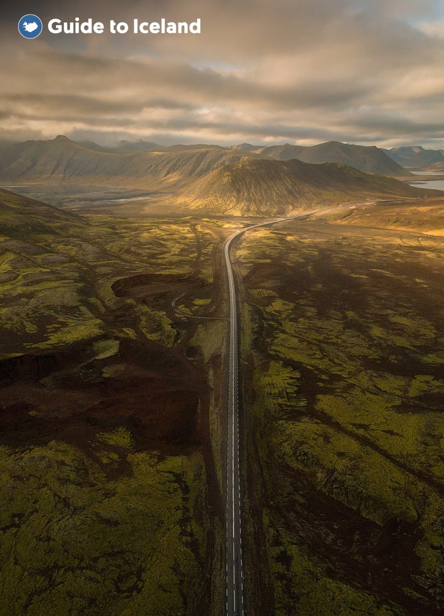 A road slices through a lava field to the coast in Iceland.