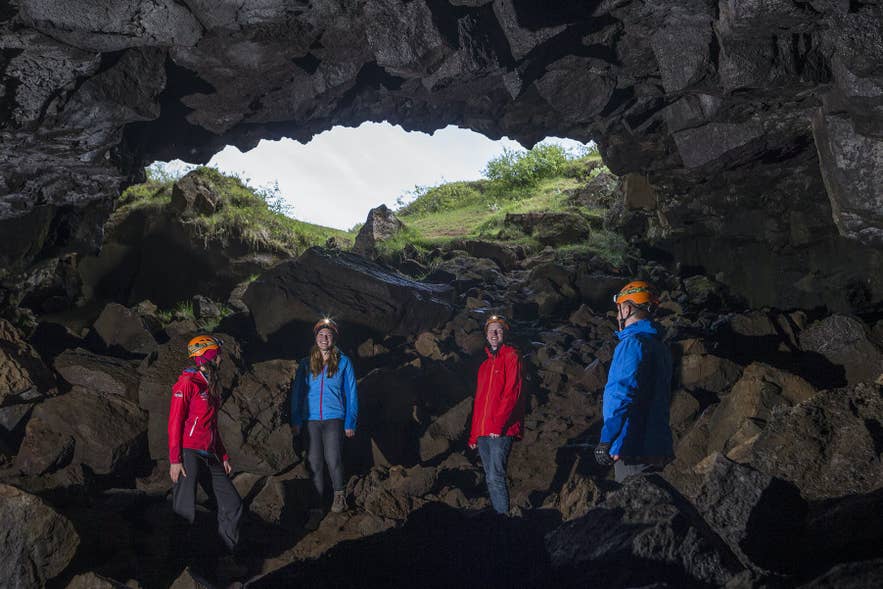 Eine Gruppe erkundet eine Lavahöhle in Island, ausgestattet mit Helmen und Stirnlampen in einer zerklüfteten vulkanischen Höhlenkammer. Eine Gruppe erkundet eine Lavahöhle in Island, ausgestattet mit Helmen und Stirnlampen in einer zerklüfteten vulkanischen Höhlenkammer.