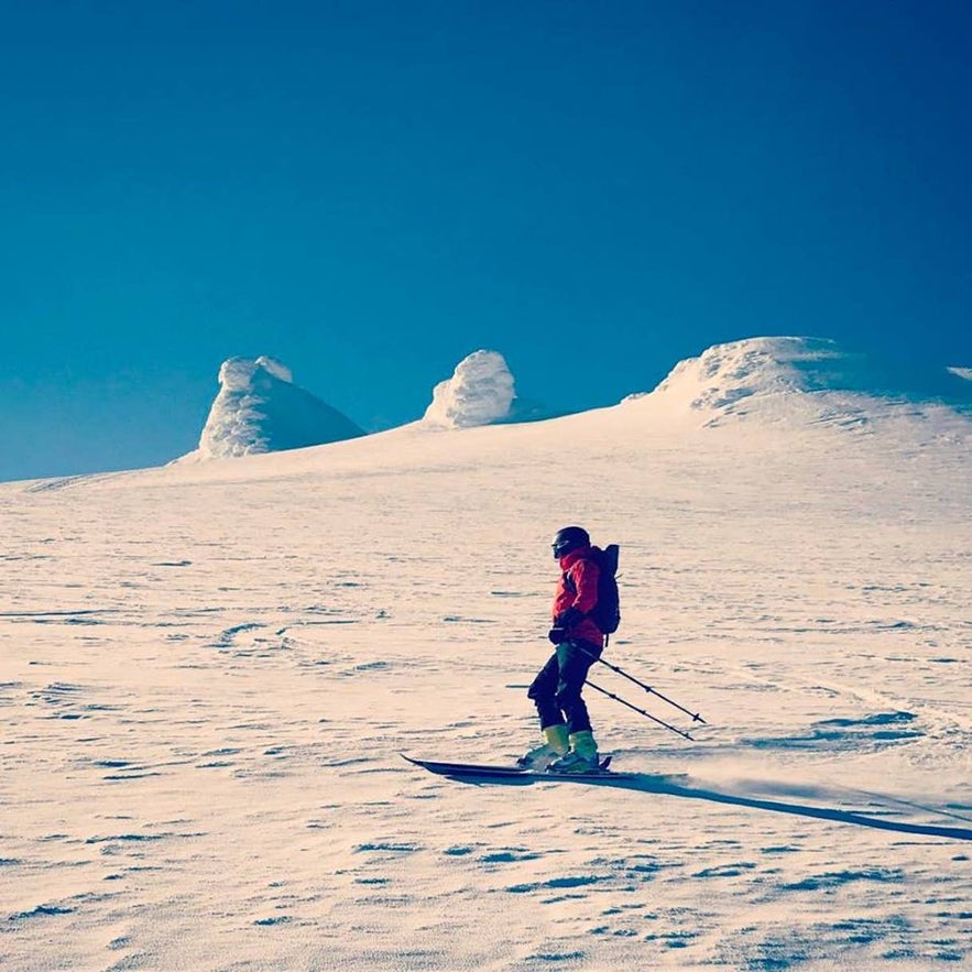 Skiing and snowboarding in Iceland on the glacier slopes of Snaefellsjokull with icy peaks in view.