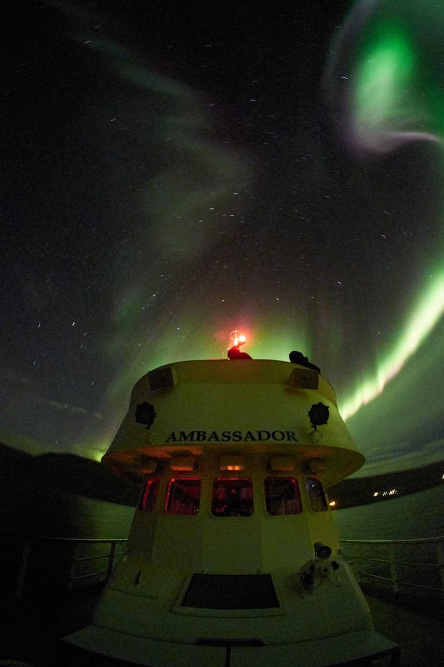 The northern lights dance over a ship in Iceland.