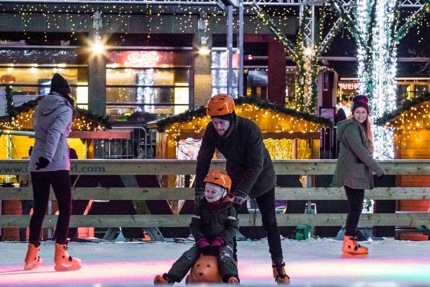 Famiglie che pattinano sul ghiaccio alla pista festiva di Reykjavik, una gioiosa tradizione natalizia in Islanda tra luci e decorazioni.