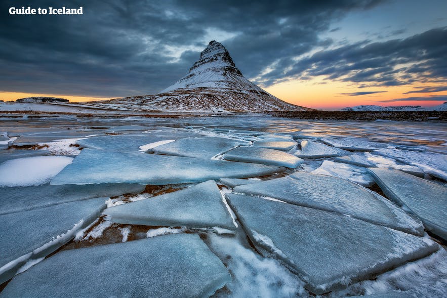 Winter view of Kirkjufell mountain in West Iceland at sunset with cracked ice in the foreground, a top photography spot and natural landmark. Winter view of Kirkjufell mountain in West Iceland at sunset with cracked ice in the foreground, a top photography spot and natural landmark.
