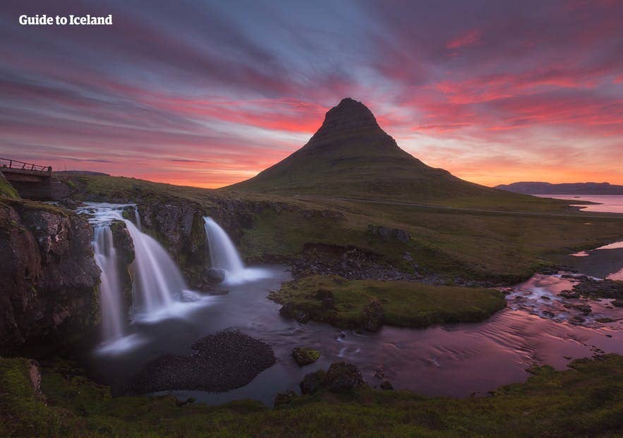 Kirkjufell mountain and Kirkjufellsfoss waterfall in Iceland at sunset, with colorful skies and a serene river flowing below.