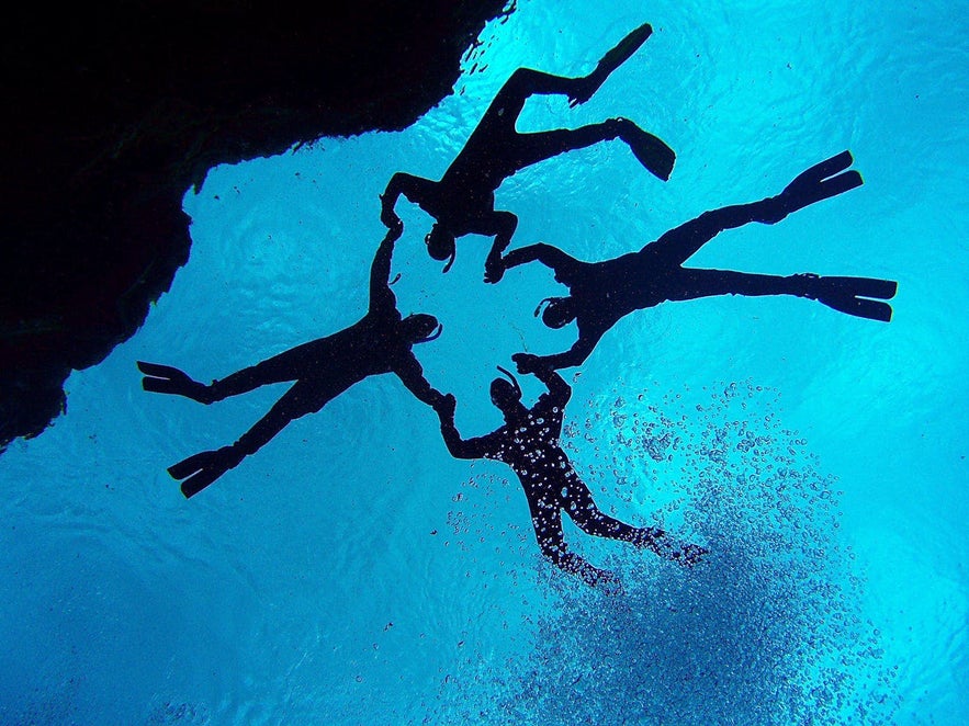 A group of snorkellers swimming through Silfra's middle section, "The Hall."