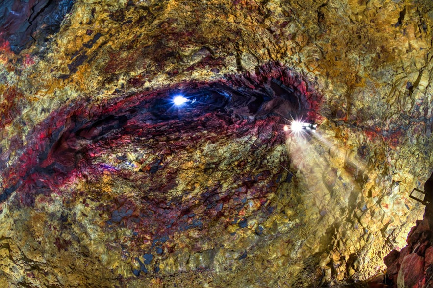 Interior view of the vividly colored magma chamber of Þríhnúkagígur volcano in Iceland, with sunlight streaming through the crater opening.