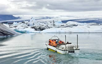 Ein Tourboot gleitet durch die ruhigen Gewässer der Gletscherlagune Jökulsárlón, umgeben von atemberaubenden Eisbergen.