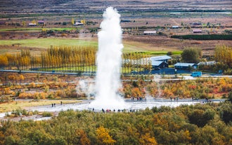 Strokkur Geyser erupts in the Geysir Geothermal Area as visitors watch from below during a Golden Circle full day tour.