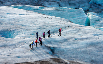 Un groupe de voyageurs marche sur la glace lors d'une randonnée glaciaire.
