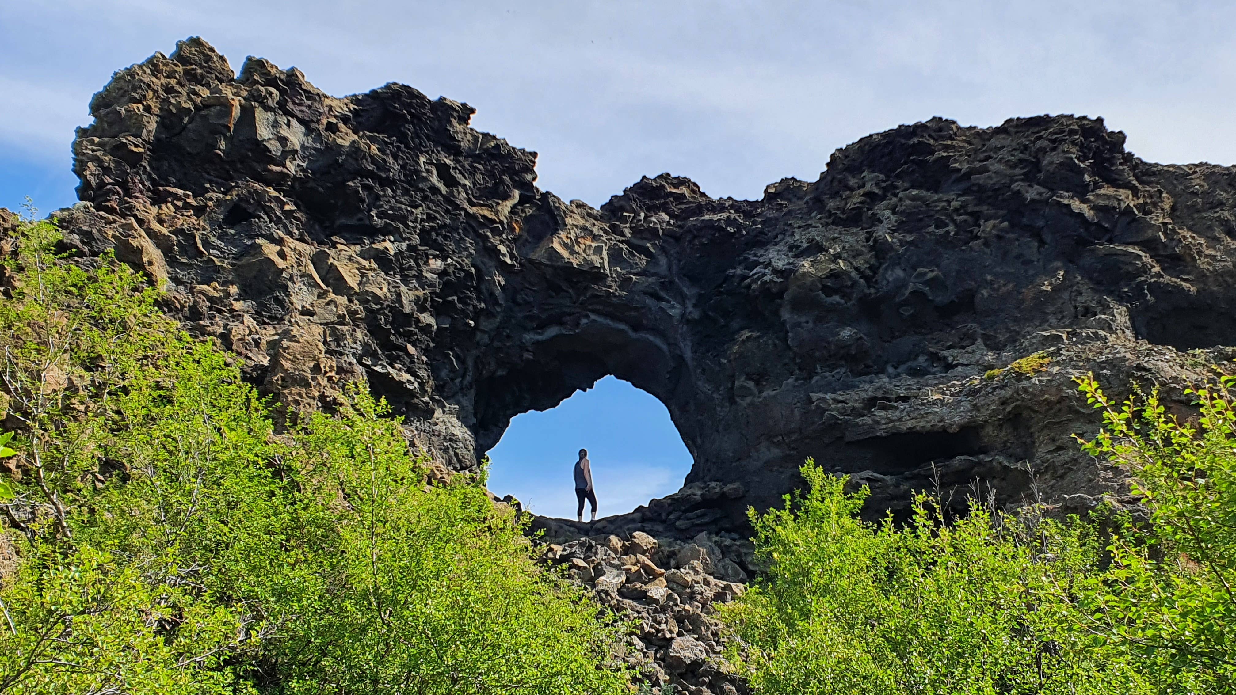Natural lava arch formation with a person standing in the opening at Dimmuborgir, Lake Myvatn.