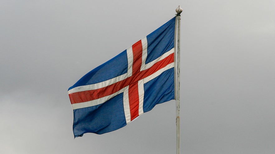 Iceland's flag flies against stormy skies.