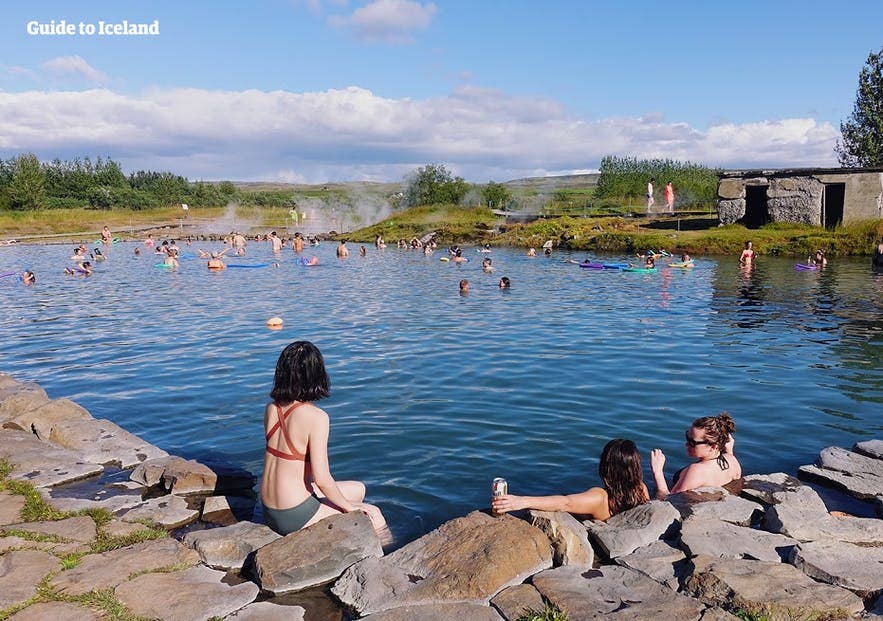 Bathers relaxing and talking in the warm water of a natural Icelandic hot spring pool.