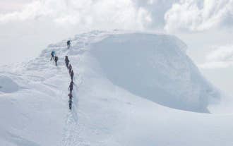 Vandrere, der overvinder de sneklædte landskaber på vulkangletsjeren Eyjafjallajökull.