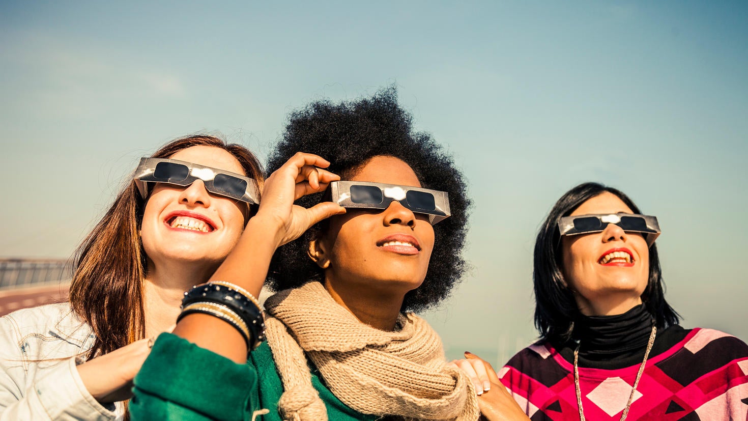 A trio of travelers wearing special glasses in preparation to see the solar eclipse in Iceland.
