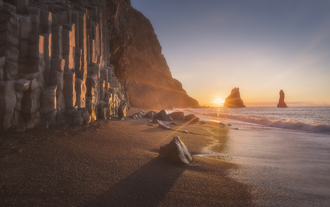 Plage de sable noir avec des falaises de basalte au loin le long de la Côte Sud de l'Islande