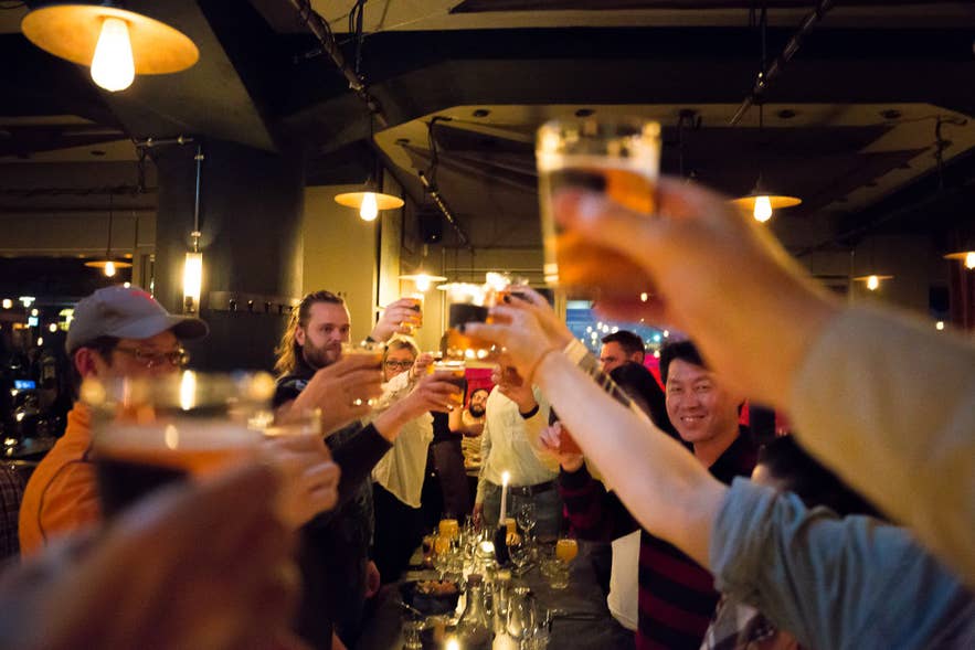 A group of friends raising their glasses together in a Reykjavik bar.