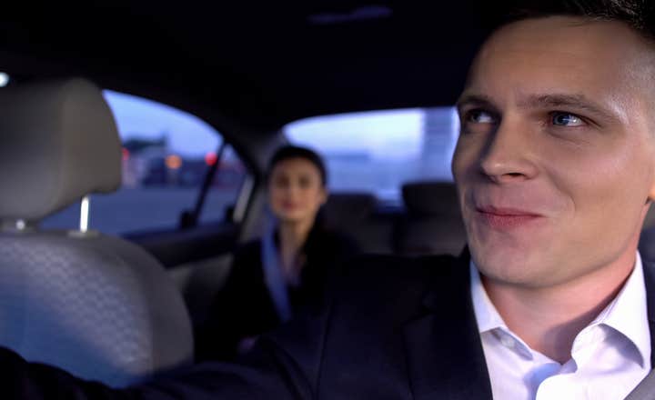 Prywatny kierowca uśmiecha się do podróżnego na tylnym siedzeniu.