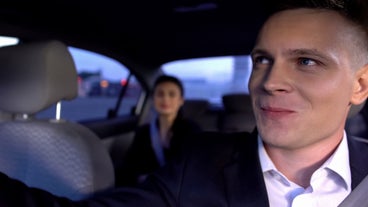 Ein Privatfahrer lächelt den Reisenden auf dem Rücksitz an.
