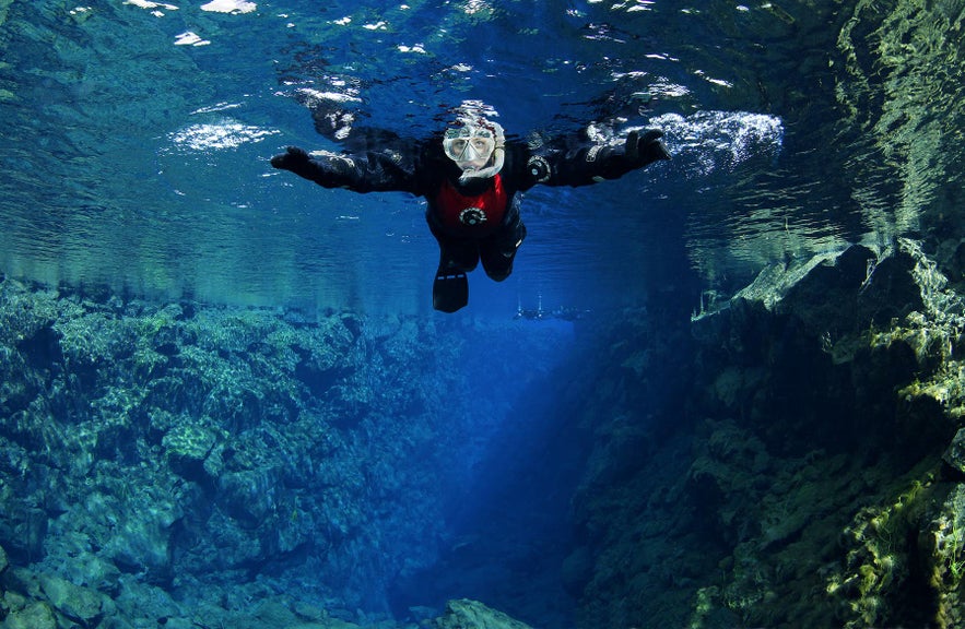 Snorkeler floating between tectonic plates in the clear waters of Silfra Fissure, Thingvellir National Park, Iceland. Snorkeler floating between tectonic plates in the clear waters of Silfra Fissure, Thingvellir National Park, Iceland.