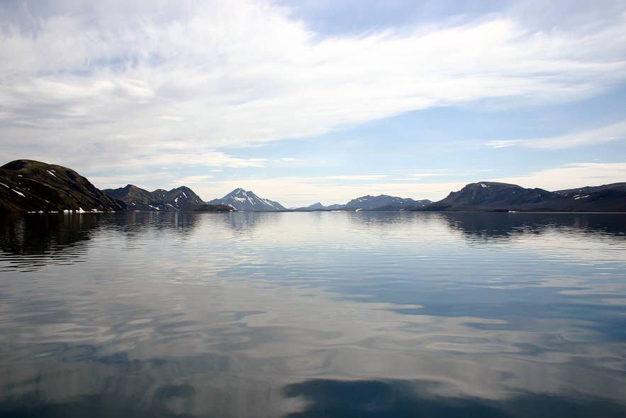 冰岛朗吉湖，宁静的倒影湖水、远处山脉和开阔的高地景观