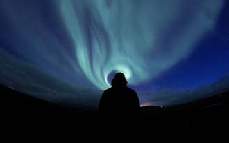 Een reiziger bewondert het poollicht in IJsland.