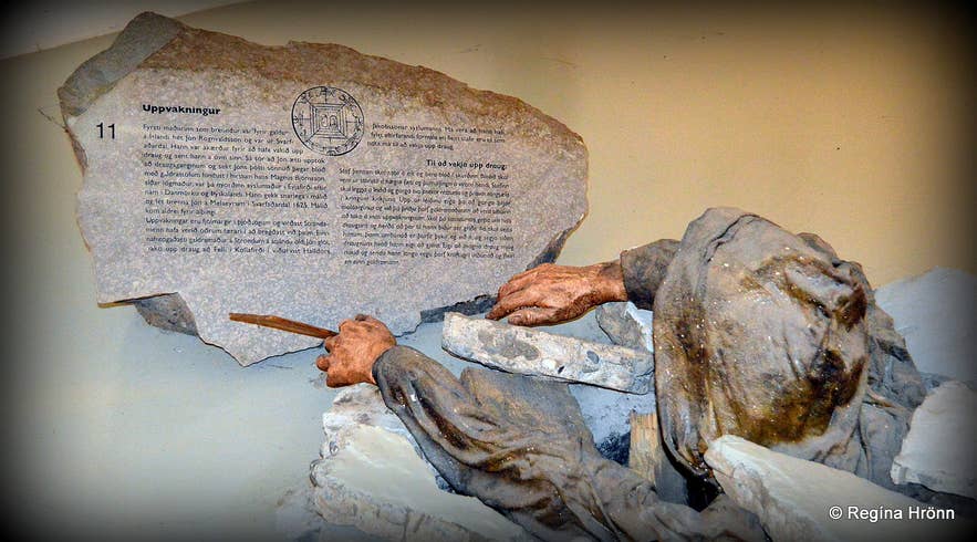 Museum exhibit showing a stone inscription and sculpted figure related to Icelandic dark arts and sorcery legends.