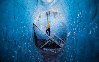 A visitor ascends wooden steps within the ice cave during a photo tour in Iceland.