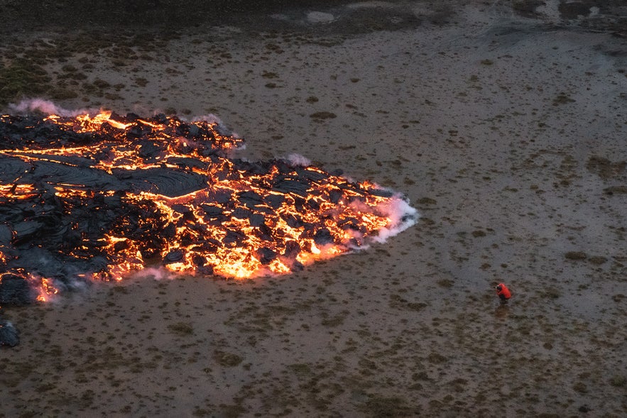 A daring photographer stands at the edge of the growing lava field at Geldingadalur.