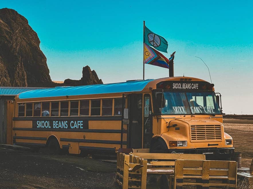 The yellow Skool Beans coffee bus in Vik near the Reynisdrangar sea stacks
