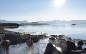 A woman with her back to the camera enjoying the warm geothermal pools of Hvammsvik Hot Springs.