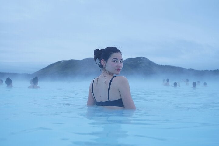 A photo of a woman looking back at the camera while soaking in the geothermal pool in the Blue Lagoon.