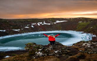 Un voyageur se tient au bord du cratère de Kerid en Islande.